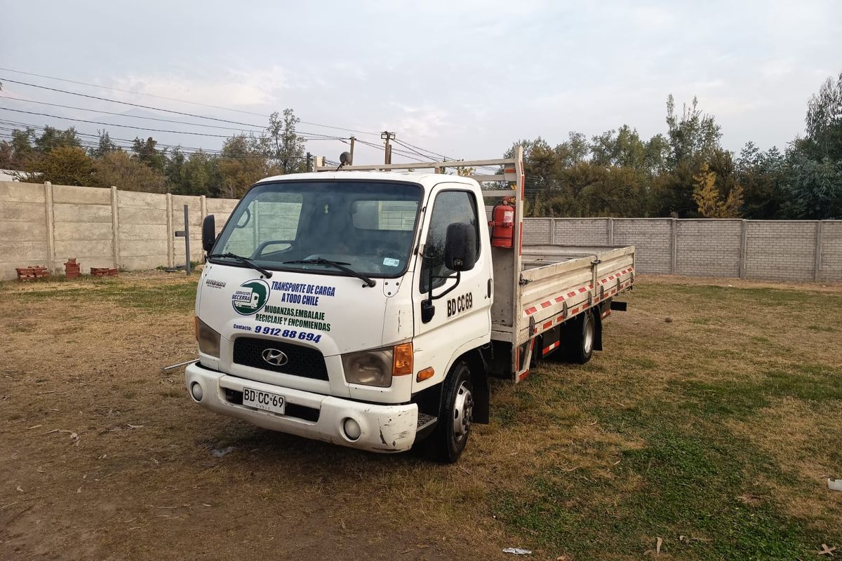 Camión plano con barandas de Servicios Becerra cargado para un flete